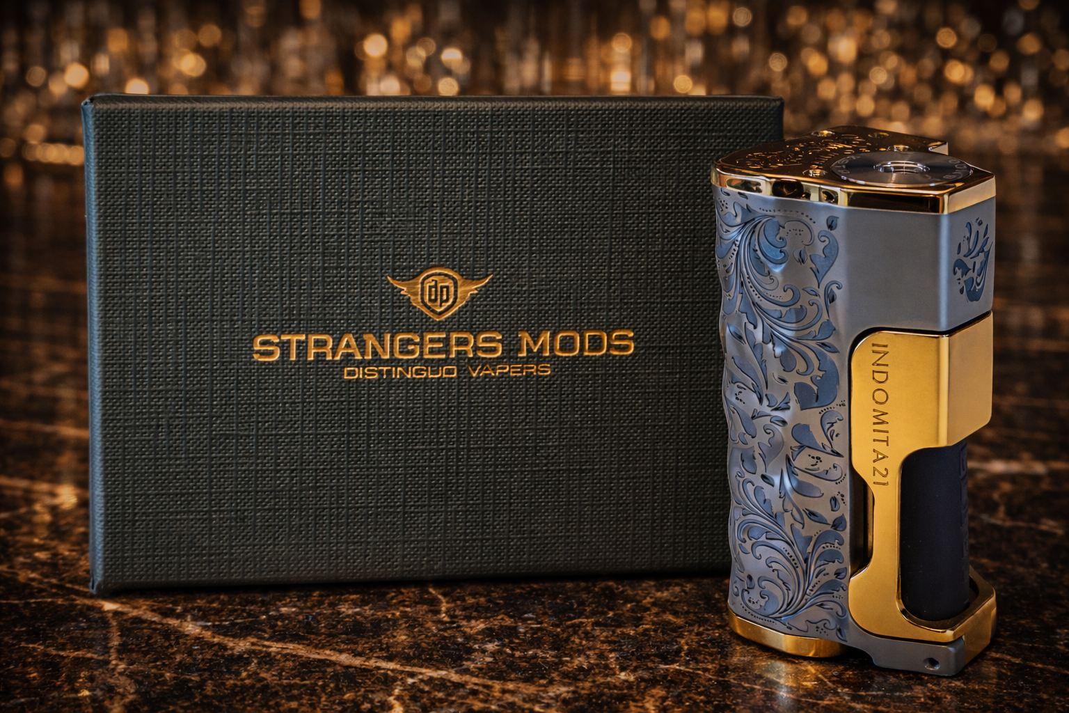 Close-up of the INDOMITA21 Pandora Modena luxury squonk mod with fully engraved metal body and gold accents, standing upright beside the box.